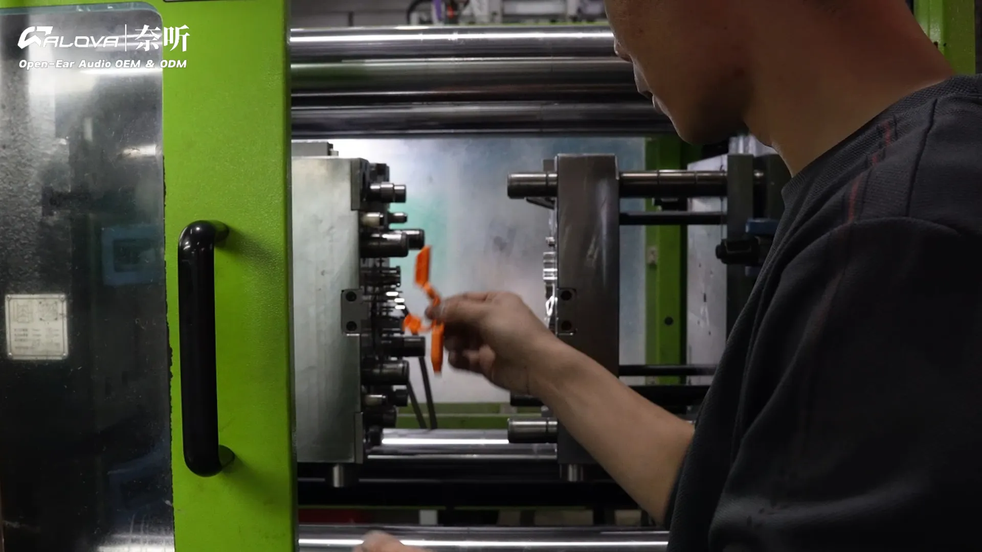 Worker sampling custom-colored open-ear headphone parts from an injection molding machine.