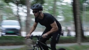 An action shot of a cyclist using open-ear headphones during a high-speed workout. The design ensures the rider can enjoy audio while maintaining situational awareness of traffic and environmental sounds, making them the safest audio solution for outdoor activities like biking and running.