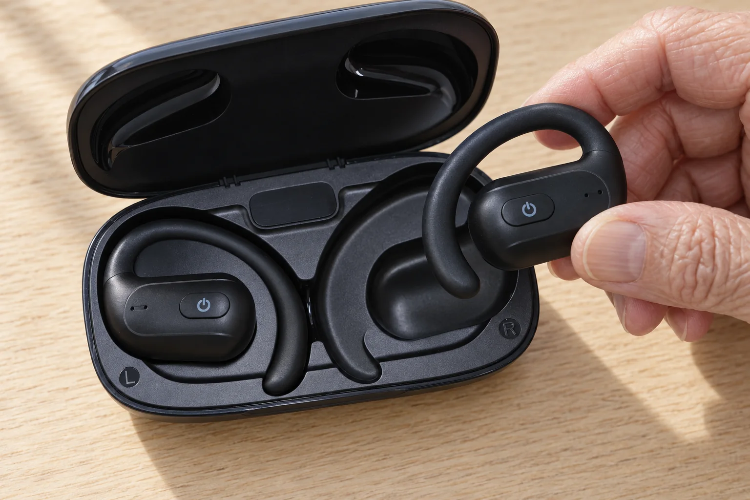 AI-generated close-up of an older hand positioning an open-ear earpiece above its charging-case recess.