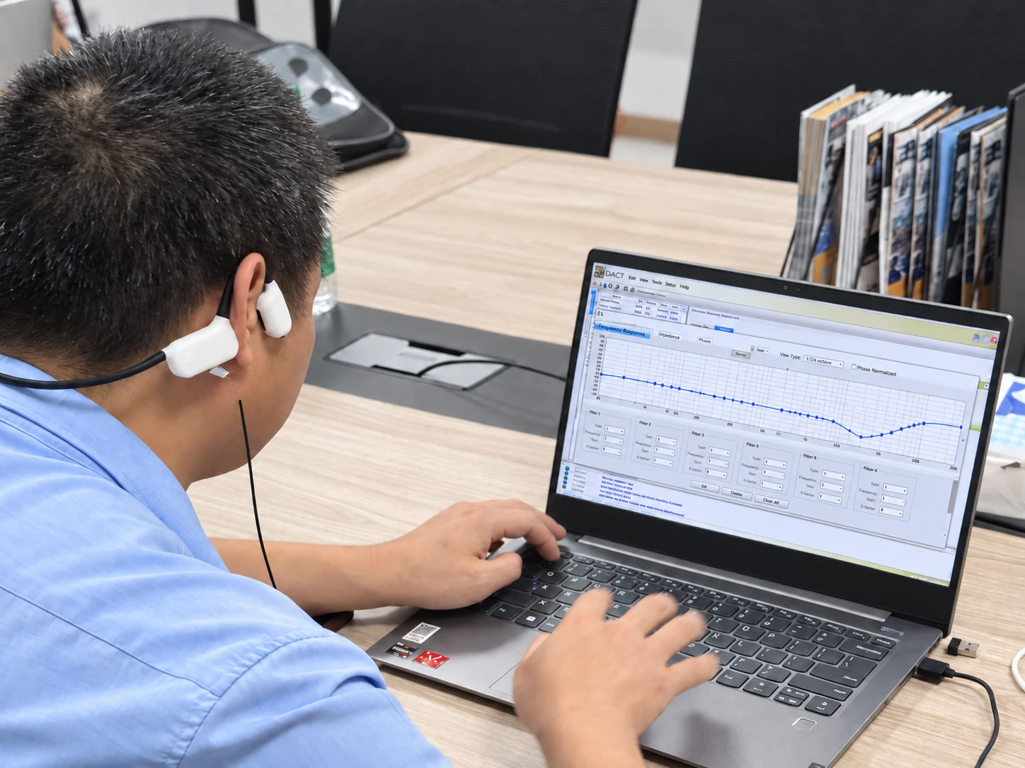 Alova奈听 engineer wearing a bone conduction device and reviewing acoustic response curves